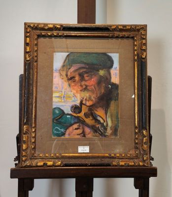 tableau représentant un vieil homme fumant la pipe, posé sur un chevalet en bois