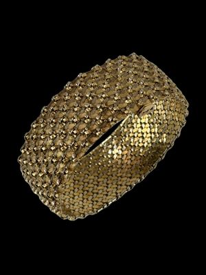 gros plan d'un bracelet en or sur fond noir