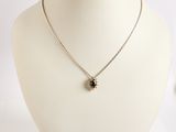 collier en argent avec un pendentif en forme de fleur noire sur un mannequin blanc