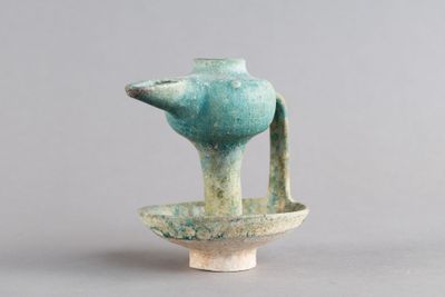 un petit vase bleu muni d'une anse, posé sur une table
