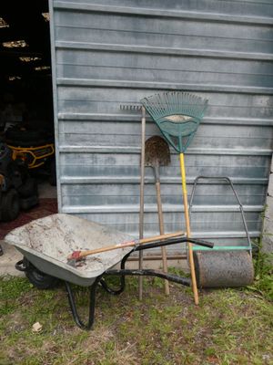 a wheelbarrow, rake and a wheelbarrow in front of a garage