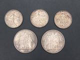 four different types of silver coins on a black surface