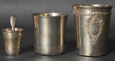 trois tasses en argent et une cuillère posées sur une table