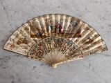un vieux ventilateur orné d'une peinture, posé sur une table
