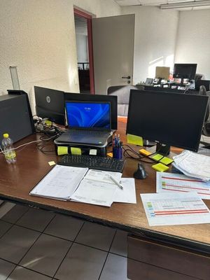 un bureau sur lequel se trouvent un ordinateur portable, un écran, un clavier, une souris et d'autres objets