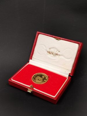 un gros plan sur une petite boîte rouge contenant une médaille d'or
