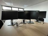 three computer monitors sitting on a desk in an office