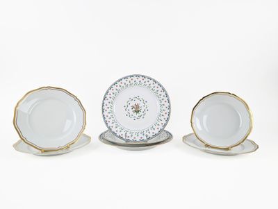 three porcelain plates and saucers with gold rims on a white background