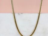 un collier à chaîne en or posé sur une surface en marbre