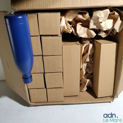 une boîte en carton contenant une bouteille en plastique bleue