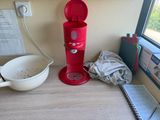 a red coffee maker sitting on a desk next to a window
