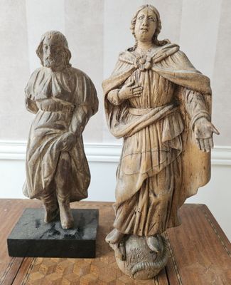 deux statues représentant une femme et un homme posées sur une table en bois