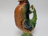 a ceramic rooster with a pipe in it ' s beak