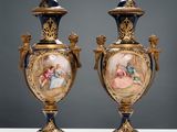 pair of antique vases with painted scenes on them sitting on a table