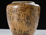 a brown vase sitting on a table with a black background