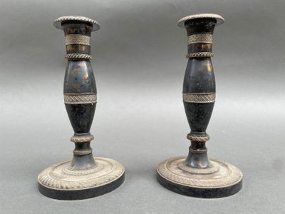 une paire de bougeoirs anciens noirs et dorés sur fond gris