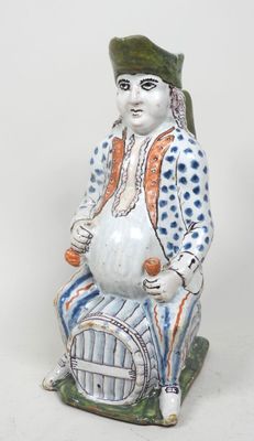 une figurine représentant un homme assis sur un tonneau