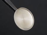 a spoon with a metal lid on a black surface