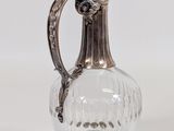 an antique silver plated glass jug with a handle on a white background