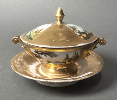 a gold plate with a lid and a saucer on it
