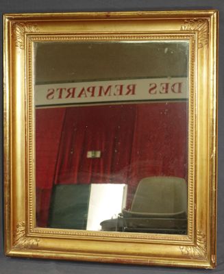un miroir à cadre doré avec un rideau rouge en arrière-plan