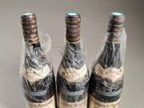 three bottles of wine wrapped in plastic wrap sitting on a table