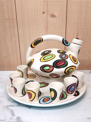 a tea pot and cups on a plate on a table