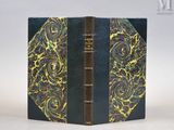 un vieux livre à la couverture dorée et noire posé sur une table
