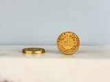 une pièce d'or posée à côté d'une autre pièce d'or sur un comptoir en marbre