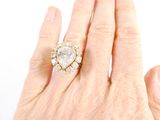 an image of a woman ' s hand holding a ring with a pear shaped diamond