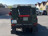 a military vehicle parked in a parking lot with other cars
