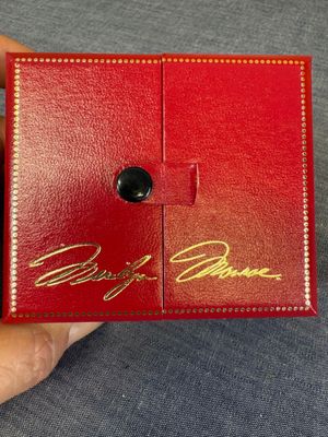 Quelqu'un tient une boîte rouge sur laquelle figure une inscription dorée.