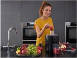 a woman that is making a fruit juice in the kitchen