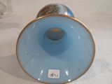 a blue vase with a gold rim sitting on a white surface