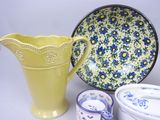 a yellow pitcher sitting next to a blue and white plate and bowls