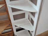 a corner shelf in the corner of a room next to a staircase