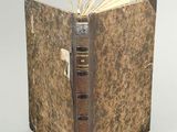 an old book that is open on a white surface