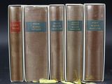 three old books are lined up on a black surface