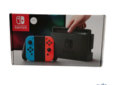 deux manettes Nintendo Switch dans une boîte, avec une main posée sur l'une d'elles