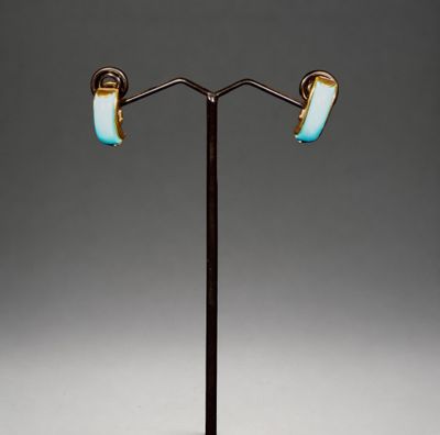 une paire de boucles d'oreilles bleues et dorées posées sur un présentoir noir