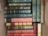 une boîte pleine de vieux livres posée sur le sol