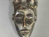 un gros plan d'un masque en bois accroché au mur
