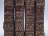 six vieux livres sont alignés sur une surface blanche