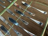 a lot of silverware on a table with a brown cloth