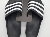 des pantoufles Adidas noires et blanches ornées de bandes blanches