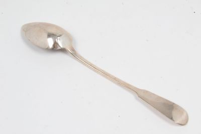 une cuillère en argent avec un manche de cuillère sur une surface blanche