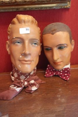 deux têtes de mannequin posées sur une table, avec un mur rouge en arrière-plan