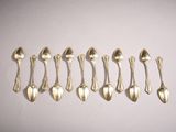 six silver spoons are lined up in a row on a white surface