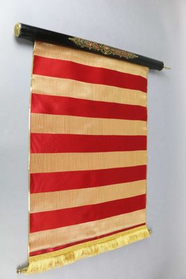 un drapeau rouge et or accroché au mur d'une pièce