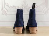 a pair of blue sued ankle boots on a wooden table